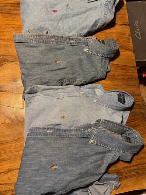 Folded blue oxford shirts on a wooden table