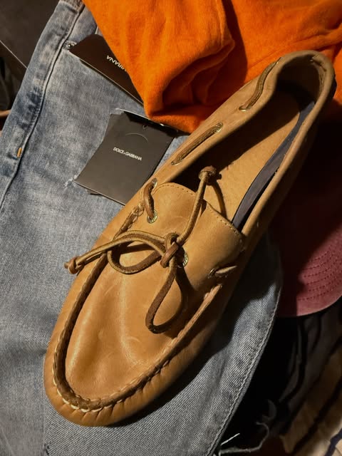 Tan leather boat shoe resting on blue jeans